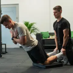 Trener pomaga w ćwiczeniu na maszynie do ćwiczeń, wspierając funkcjonalny trening siłowy.