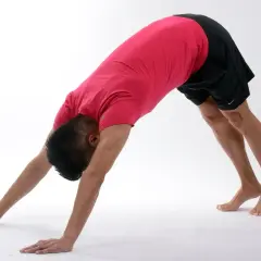 Mężczyzna w pozycji psa z głową w dół, wykonuje ćwiczenia na mięśnie głębokie brzucha.
