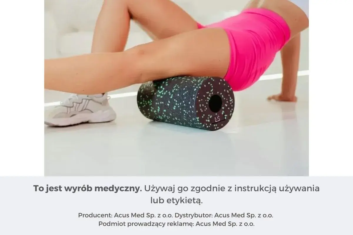 Kobieta wykonuje rolowanie mięśni ud za pomocą czarnego wałka z zielonymi kropkami.