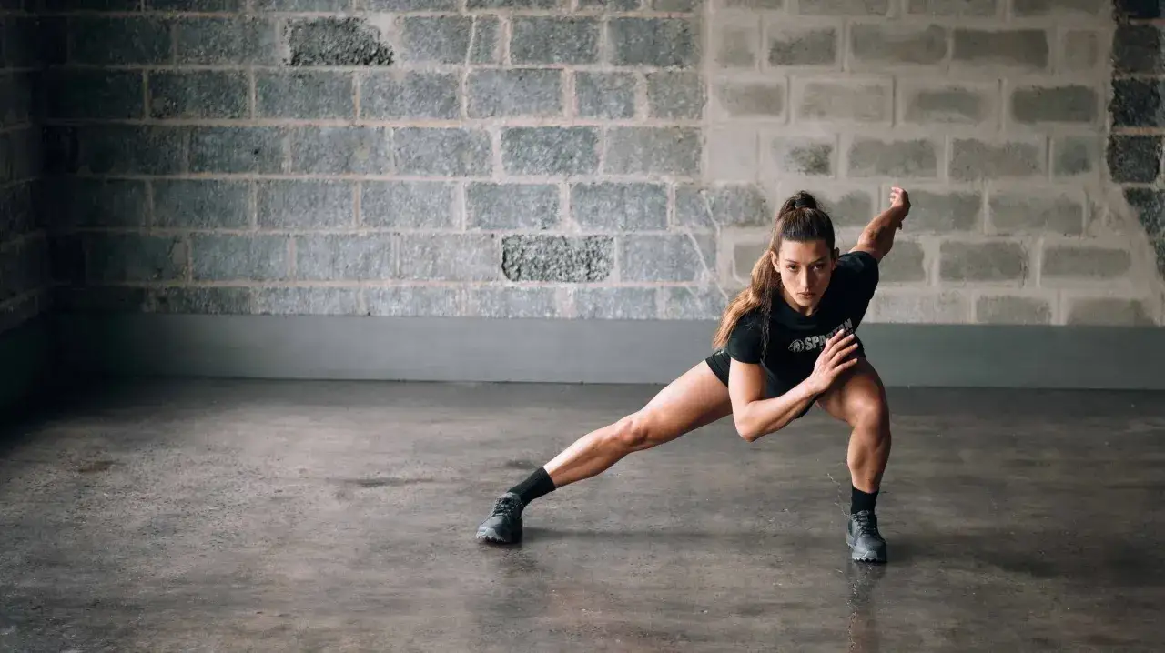 Kobieta w pozycji wykroku bocznego, ćwicząca crossfit.