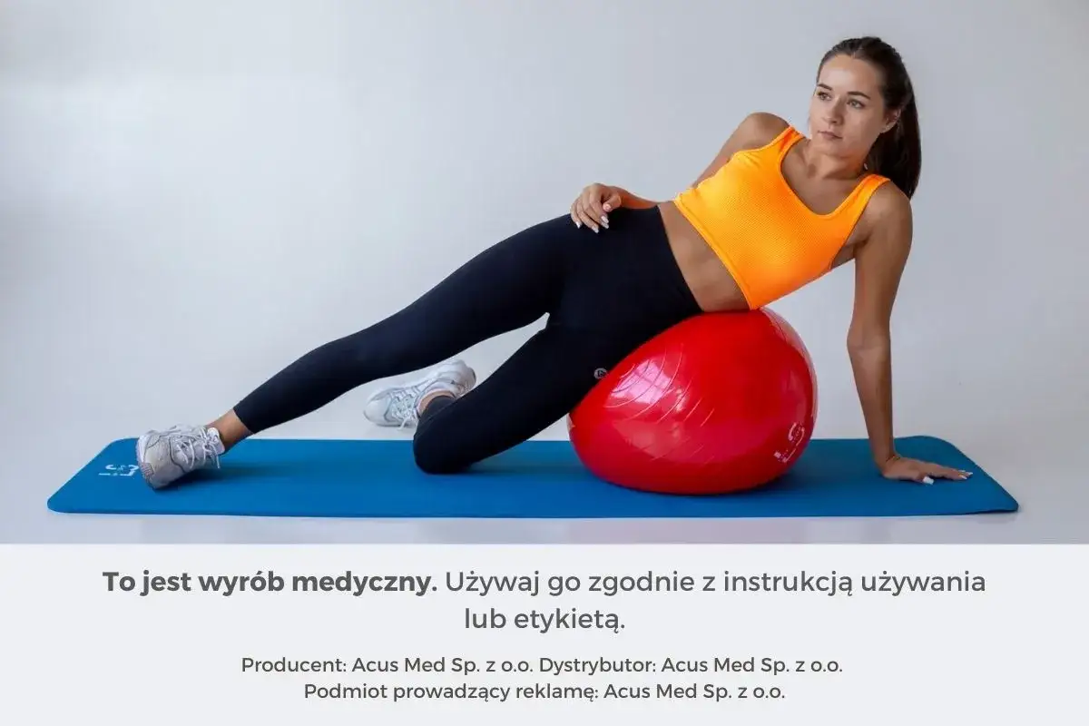 Kobieta wykonuje ćwiczenia z piłką gimnastyczną, leżąc na macie.